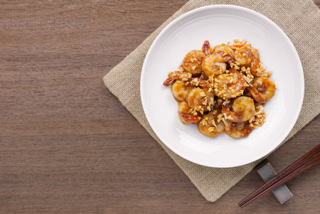 top view of stir fried shrimp with garlic and spicy sweet sauce in a ceramic dish on wooden table. asian homemade style food concept.の写真素材