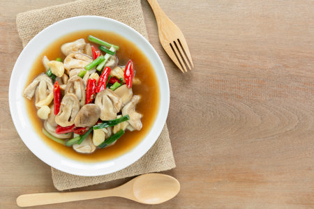 top view of stir fried straw mushroom with oyster sauce in a ceramic dish on wooden table. asian homemade style food concept.の写真素材