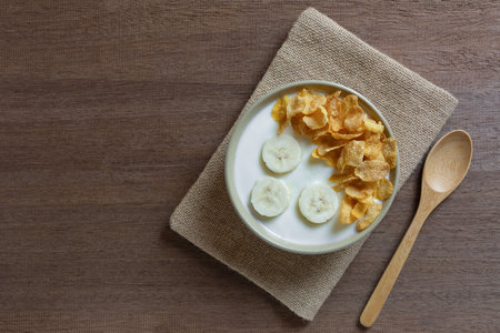 top view of natural yogurt with banana and corn flakes in a ceramic bowl on wooden table, copy space. healthy food concept.の写真素材