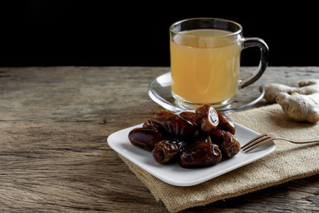 dried date palm fruits served with ginger tea on wooden table.の写真素材