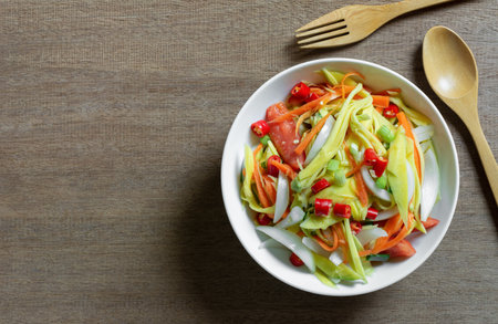 top view of spicy mango salad in a ceramic bowl on wooden table. asian homemade style food concept.の写真素材