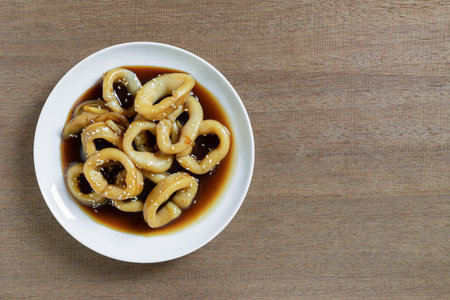 top view of stir fried squid with teriyaki sauce in a ceramic dish on wooden table, copy space. asian homemade style food concept.の写真素材