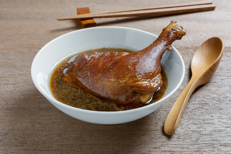 boiled duck thigh with sweet brown soup in a ceramic bowl on wooden table, close up. asian homemade style food concept.の写真素材