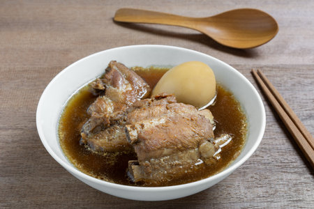 boiled pork rib and duck egg with sweet brown soup in a ceramic bowl on wooden table, close up. asian homemade style food concept.の写真素材