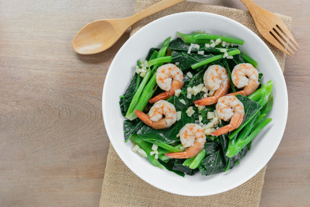 top view of stir fried chinese kale with shrimps in a ceramic bowl on wooden table. asian homemade style food concept.の写真素材