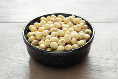 close up of lotus seeds in a ceramic bowl on wooden table.の写真素材
