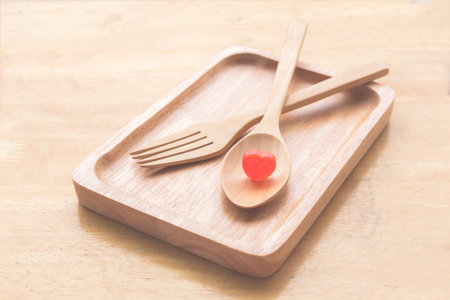 Red candy heart in the wooden spoon and dishの写真素材