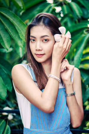 asian beautuful woman put Plumeria flower in her hairの写真素材