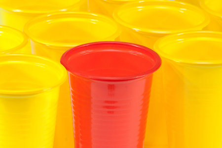 Glasses plastic yellow and red are on the kitchen tableの写真素材