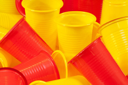 Glasses plastic yellow and red are on the kitchen tableの写真素材