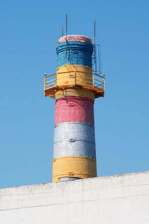 Painted brick chimney with a ladder against the blue sky