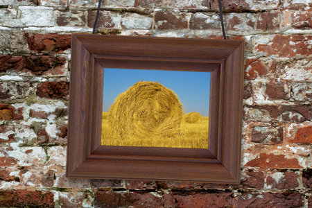 Painting in a wooden frame hanging on an old brick wallの写真素材