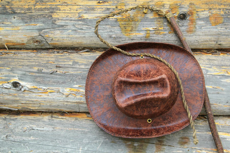 Leather hat and whip hanging on the wall of a wooden houseの写真素材