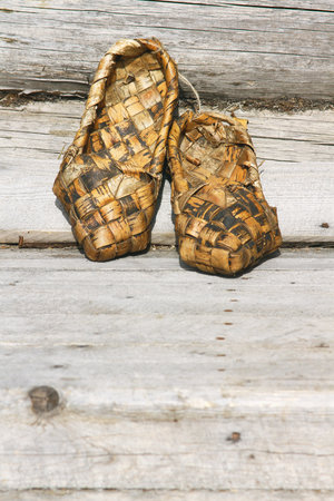 Russian bast shoes on the background of an old village house wall の写真素材