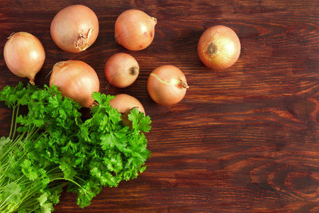 Onions and parsley on a wooden kitchen tableの写真素材