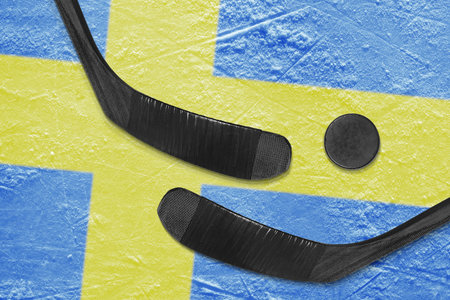 Hockey puck, hockey sticks and a picture of the Swedish flag on the ice. Conceptの写真素材