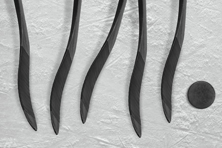 Hockey puck and five sticks on the ice of the hockey fieldの写真素材