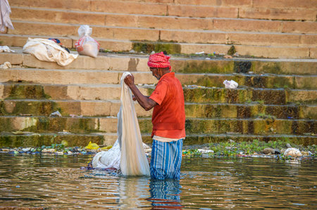 Man Doing Early Morning Laundry Ganges River in Varanasi, Indiaのeditorial素材