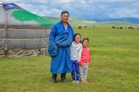 Mongolian Nomad with his two daughters standing near his Ger or Yurt with his animals in the background.のeditorial素材