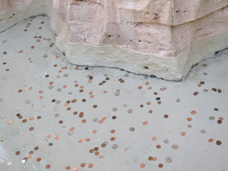 Many different coins under water in a fountain