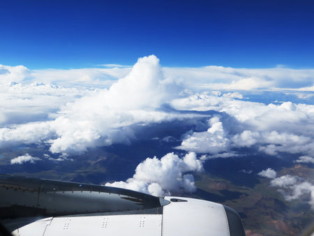 Wing of the plane on blue sky and clouds backgroundの写真素材