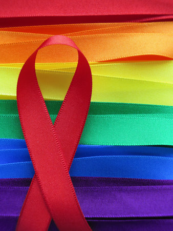 AIDS awareness red ribbon on gay flag background