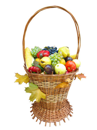 wooden basket with autumn harvest fruit vegetables and leaves isolatedの写真素材