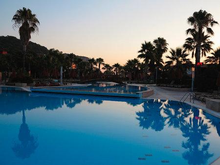 Luxury swimming pool and palms in the tropical resort hotel in the sunsetのeditorial素材