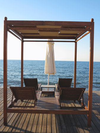 Beach chairs and umbrella on the sand near sea, blue sky and horizonの写真素材