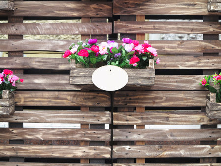 Old brown wooden fense with red flowers in boxesの写真素材
