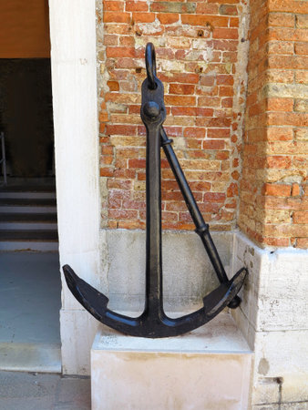 ancient iron black anchor over red brick wall background.の写真素材