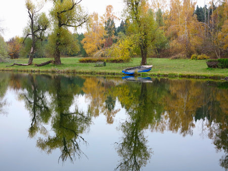 Autumn landscape with colorful forest, lake, reflection and a boatの写真素材