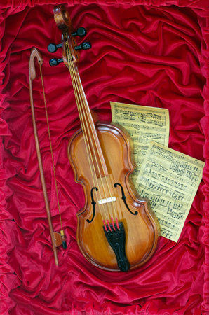 Violin music concept and sheet music on red canvasの写真素材