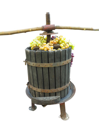 Old traditional manual wine press utensil with grape bunch isolated over white backgroundの写真素材