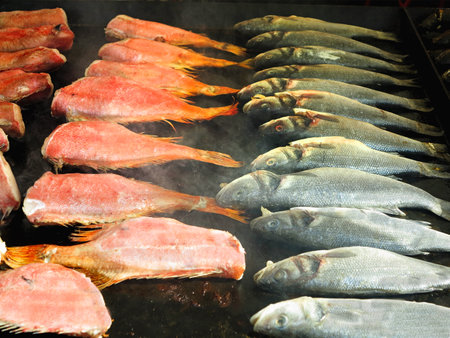 Barbeque fried fish with spices on fire grill with smoke closeupの写真素材