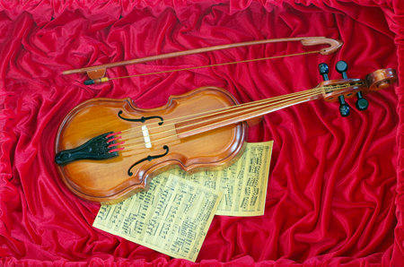 Violin music concept and sheet music on red canvasの写真素材
