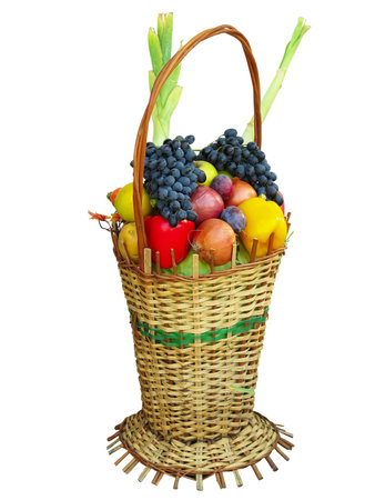 Wicker basket filled with colorful organic vegetables fresh harvest plums, grapes and apples isolated on whiteの写真素材