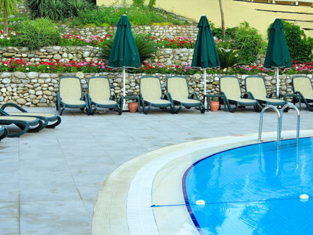 Sun loungers at water front of a swimming pool for relaxation and recreation.の写真素材