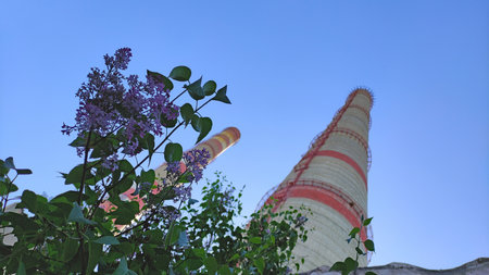 Power plant chimneys against blue sky and green leaves and flowers, no smoke, pollutionの写真素材