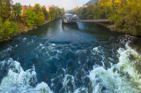 Mur river in autumn, with Murinsel bridge and old buildings in the city center of Graz, Styria...