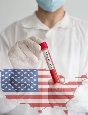 Coronavirus conceptual photo with doctor wearing a medical face mask and gloves, holding a blood test for the COVID-19 pandemic and national flag of United States of America, blurred backgroundの写真素材