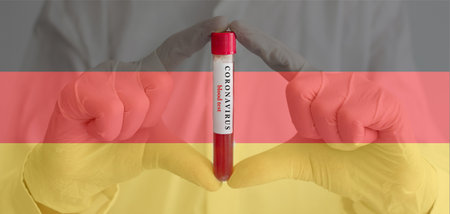 Coronavirus conceptual photo with doctor hands wearing medical gloves holding a blood test result for the COVID-19 pandemic and national flag of Germany, blurred backgroundの写真素材