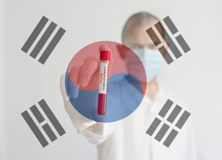 Coronavirus conceptual photo with doctor wearing a medical face mask and gloves, holding a blood test result for the COVID-19 pandemic and national flag of South Korea, blurred backgroundの写真素材