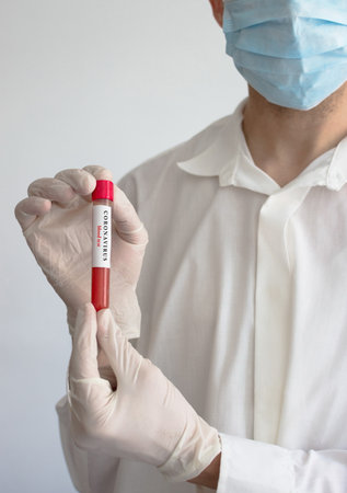 Doctor wearing a medical face mask and gloves, holding a blood test result for the Coronavirus COVID-19 outbreak. Coronavirus blood test conceptual photo.の写真素材