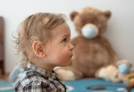Child playing with his sick teddy bears wearing medical mask against viruses. Role playing, child playing doctor with plush toy. Children and flu, coronavirus illness concept. Selective focusの写真素材