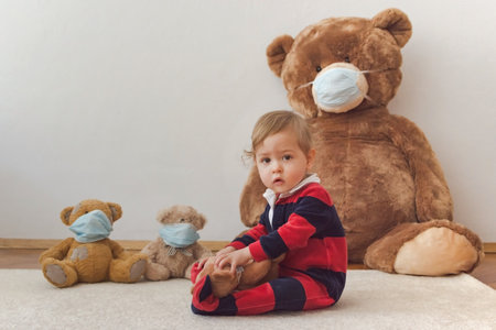 Child playing with his sick teddy bears wearing medical mask against viruses. Role playing, child playing doctor with plush toy. Children and illness concept.の写真素材