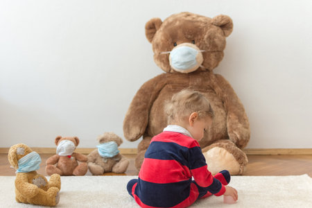 Child playing with his sick teddy bears wearing medical mask against viruses. Role playing, child playing doctor with plush toy. Children and illness concept.の写真素材