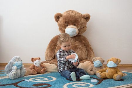 Child playing with his sick teddy bears wearing medical mask against viruses. Role playing, child playing doctor with plush toy. Children and flu, coronavirus illness concept. Selective focusの写真素材