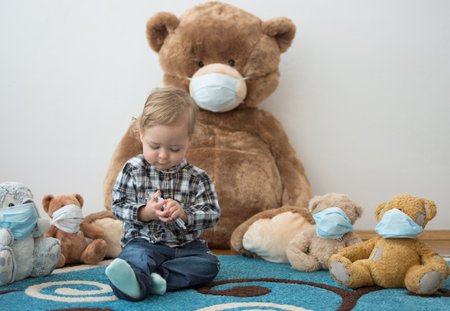 Child playing with his sick teddy bears wearing medical mask against viruses. Role playing, child playing doctor with plush toy. Children and flu, coronavirus illness concept. Selective focusの写真素材