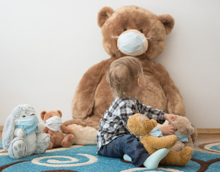 Child playing with his sick teddy bears wearing medical mask against viruses. Role playing, child playing doctor with plush toy. Children and flu, coronavirus illness concept. Selective focusの写真素材